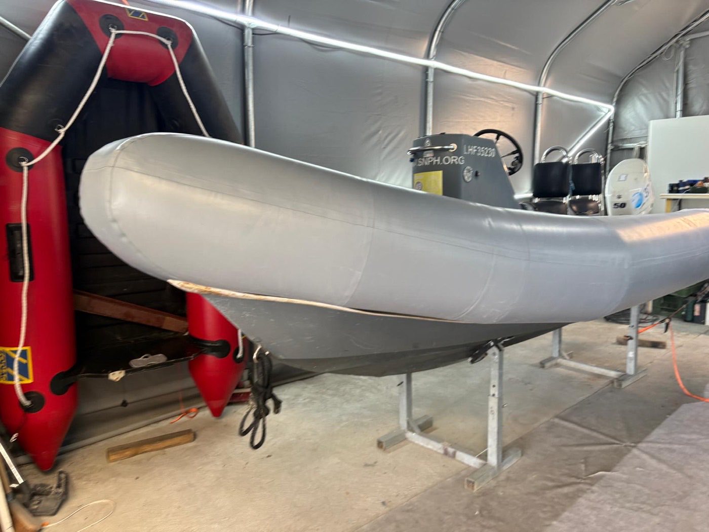 Semi-rigide gris sur ber dans l'atelier RMS à Taden, bateau pneumatique rouge en arrière-plan